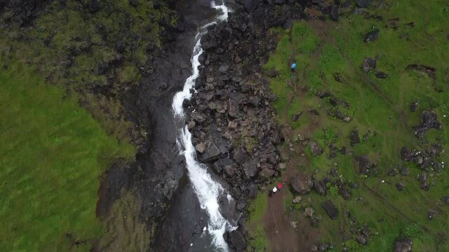 Majestic Foss&aacute; waterfall surrounded by thick fog and rugged Nordic landscape, cinematic drone shot.