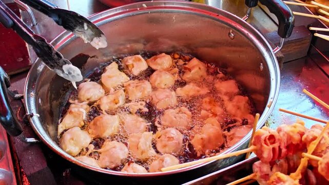 Traditional Indonesian fried snacks are displayed at a street food stall while a vendor fries them for customers. Authentic local cuisine featuring crispy homemade snacks and a vibrant street food cul