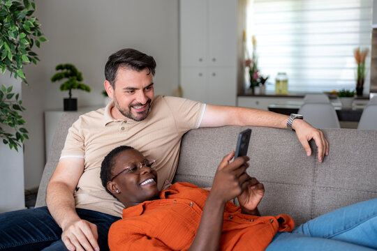 Couple enjoys time together while looking at a phone in a cozy living room