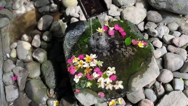 Decorative stone fountain with colorful flowers and pebbles