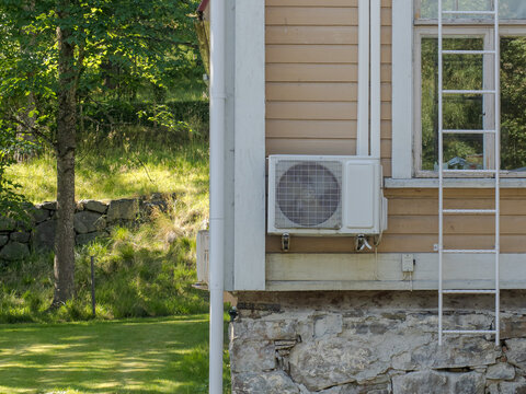Air source heat pump outdoor unit installed on the exterior wall of a residential house.