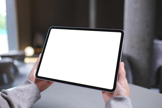 Mockup image of a woman holding digital tablet with blank white desktop screen in cafe