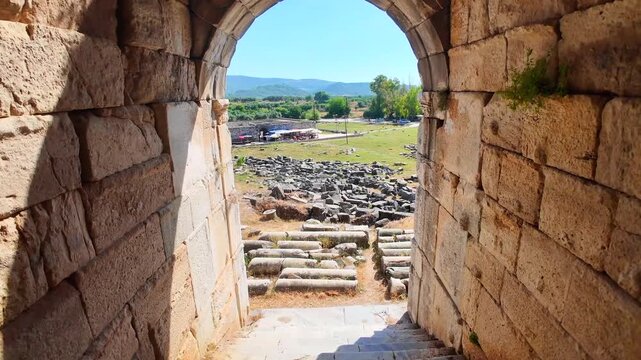 Looking down stone stairs through an ancient vaulted archway at the Miletus theater ruins towards the archaeological site outside.