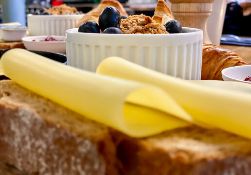 Eating breakfast food inside a caf&eacute; at the table, fried egg, yellow yolk served in a frying pan, cheese slices, croissant and fresh berries in a bowl. Depth of field blurred background. 