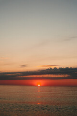 Sunset over calm ocean with warm hues on the horizon, reflective water, quiet sky, and gentle waves. Ideal for nature, travel, and relaxation themes. © SHOTPRIME STUDIO