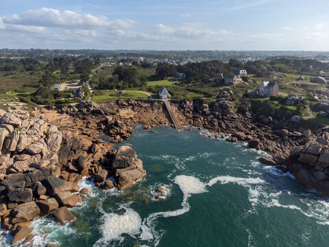 Aerial view, Lighthouse of Heap of Ploumanac'h and Chateau de Costaeres iconic pink granite rock formation on C&ocirc;te de Granit Rose, Brittany. Massive balanced boulders on seashore, France