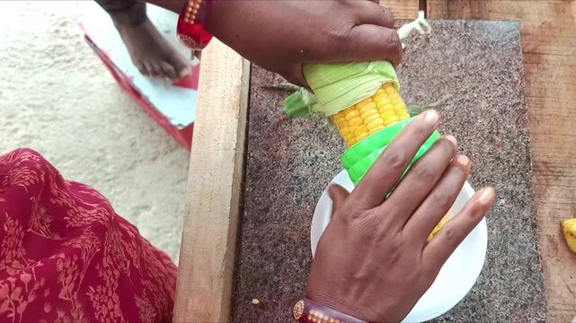 Indian street food vendor preparing spicy sweet corn chat with masalas and lemon juice