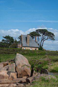 Heap of Ploumanac'h and Chateau de Costaeres iconic pink granite rock formation on C&ocirc;te de Granit Rose, Brittany. Massive balanced boulders creating natural sculptural monument on seashore, France