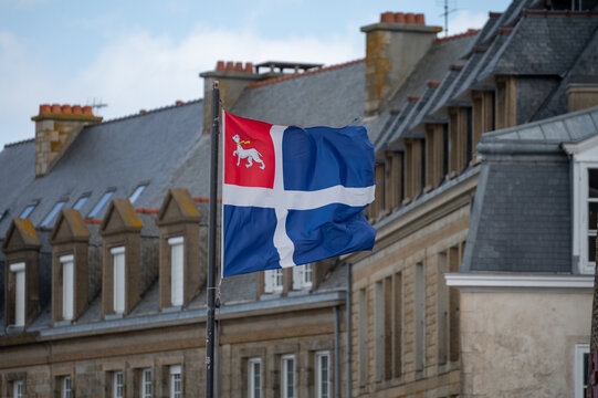 Walking along Saint-Malo ramparts in Brittany with panoramic Atlantic Ocean, houses, beach views. Historic walled city fortifications overlooking Emerald Coast sandy shores, flag of Saint-Malo