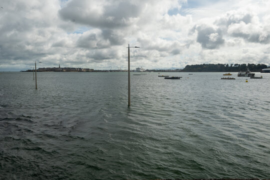 High tide in Dinard, Brittany with view toward walled city of Saint-Malo. Coastal Atlantic landscape with boats and dramatic tidal range of Emerald Coast, France.