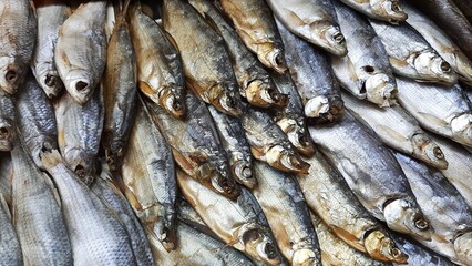 Obraz premium A selection of dried and smoked fish—a traditional beer snack. A close-up of freshly prepared fish delicacies, including Caspian roach, sabrefish, whitefish, and other varieties. Natural scale texture