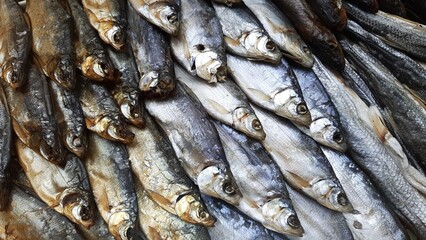 Obraz premium A selection of dried and smoked fish—a traditional beer snack. A close-up of freshly prepared fish delicacies, including Caspian roach, sabrefish, whitefish, and other varieties. Natural scale texture