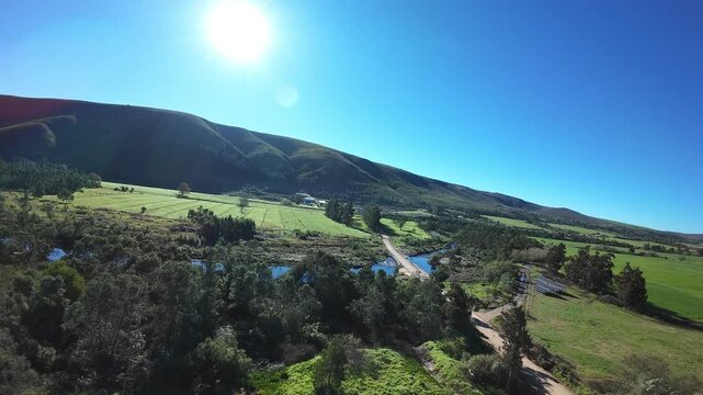 Aerial shot of two mountain bikers cycling over a bridge crossing a lush river.