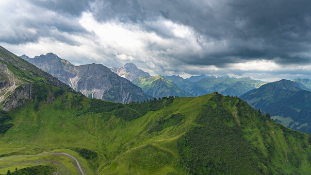 mountain range from little valley of Walser with green meadows and steep rocky slope in the alps of Bregenzerwald, with rocky mountains and steep, stony slopes on a rainy day with clouds.