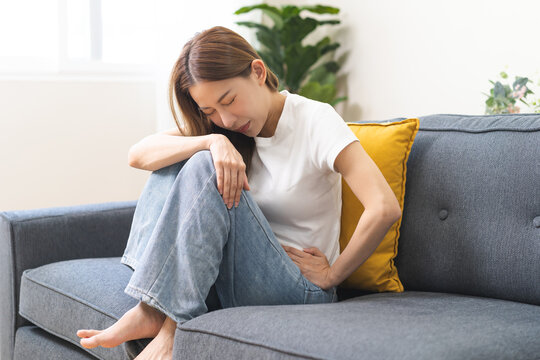 Sick asian young woman in pain, hand holding belly, stomach pain from food poisoning, girl hurt abdomen ache and digestive problem, gastritis or diarrhea. Health care inflammation, abdominal problem