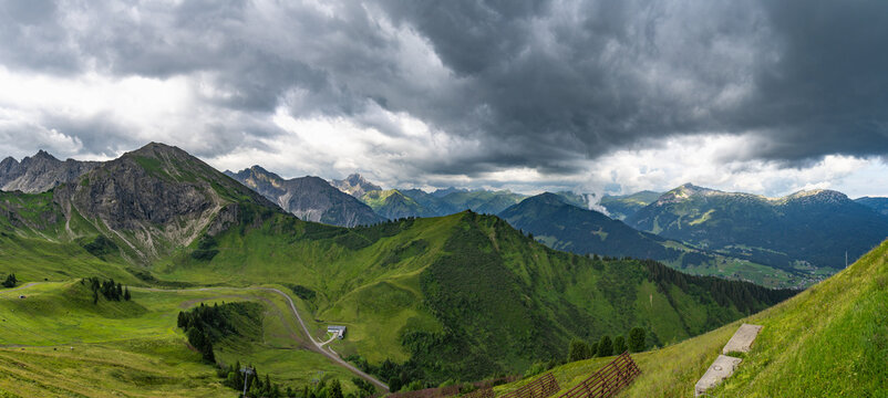 mountain range from little valley of Walser with green meadows and steep rocky slope in the alps of Bregenzerwald, with rocky mountains and steep, stony slopes on a rainy day with clouds.