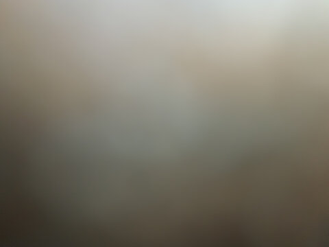 Abstract moody warm grey and beige blurred background with soft smoky texture and vintage fine art studio portrait lighting effect.