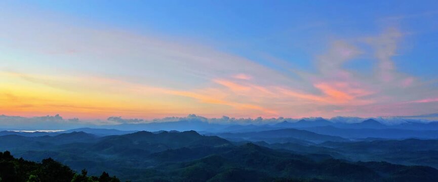 A sweeping panoramic view of densely forested mountains stretching to the horizon under a clear blue sky with soft sunlight. Beautiful natural scenery, ideal for nature, conservation, ecotourism. 4K
