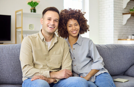 partners man woman smiling together at home. Relaxed portrait on a cozy sofa in light living room, showing affection, comfort, connection. Strong and relationship lifestyle concept.