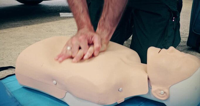 CPR first aid training demonstration - Cardiopulmonary emergency resuscitation medical procedure on dummy. Teaching chest compression technique to students learning via mannequin doll