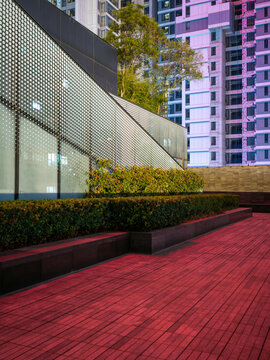 Red wooden deck and planter boxes near modern building with perforated metal facade