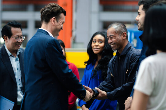 Business collaboration in manufacturing. Executives and factory professionals exchange a handshake during an industrial meeting. Partnership, teamwork, leadership, industry, collaboration