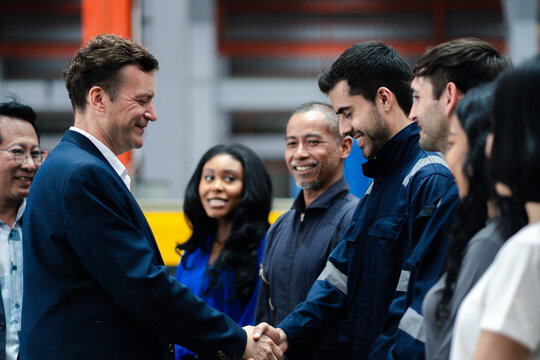 Business collaboration in manufacturing. Executives and factory professionals exchange a handshake during an industrial meeting. Partnership, teamwork, leadership, industry, collaboration