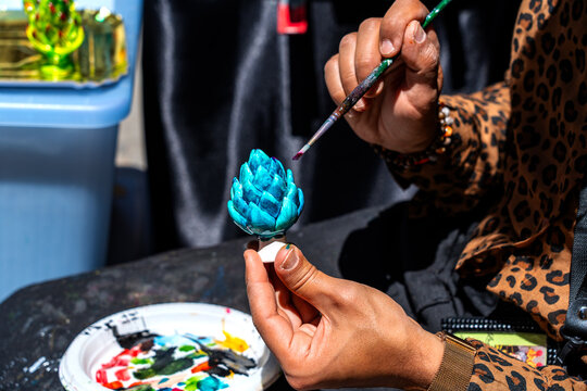  the skilful hands of a craftsman painting the traditional Sicilian ceramic pine cone &ndash; a symbol of good luck &ndash; in bright colours