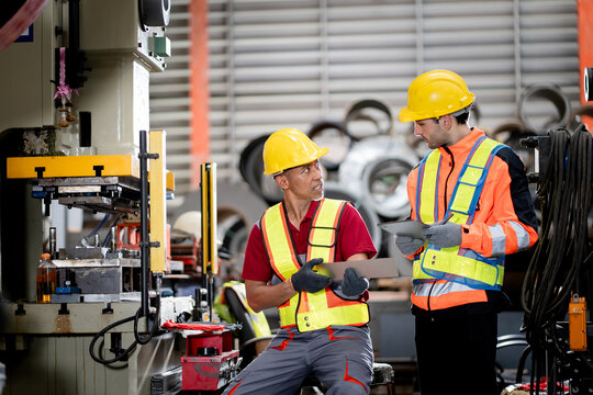 professional engineer,worker,technician use clipboard discuss work, walk in steel metal manufacture factory plant industry. Black African American man and woman wear hard hat check quality machine.
