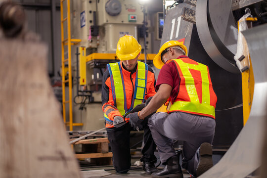 professional engineer,worker,technician use clipboard discuss work, walk in steel metal manufacture factory plant industry. Black African American man and woman wear hard hat check quality machine.