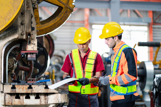 professional engineer,worker,technician use clipboard discuss work, walk in steel metal manufacture factory plant industry. Black African American man and woman wear hard hat check quality machine.