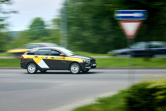 Minsk, Belarus - May 28 2021: Lada Vesta station wagon taxi driving fast on city street, Yandex Go livery, motion blur background, traffic sign, urban public transportation, passenger car.