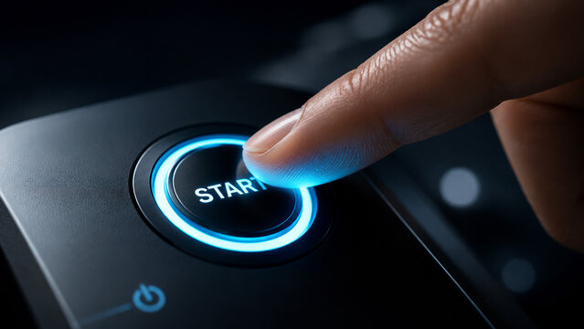 Close‑up of a finger pressing an illuminated circular START button surrounded by a glowing blue ring symbolizing initiation power‑on and beginning a modern technological process.