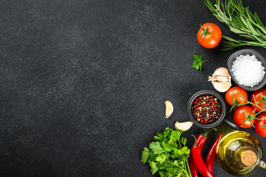 Food background on black. Fresh herbs, spices and vegetables on black table.