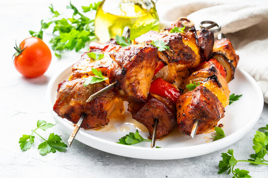 Grilled meat on skewers on light stone table.