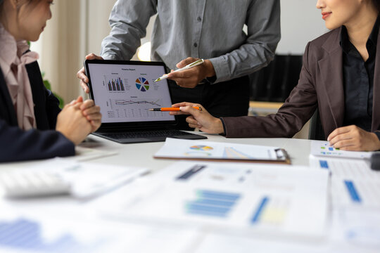 Business team analyzing financial data on laptop screen.