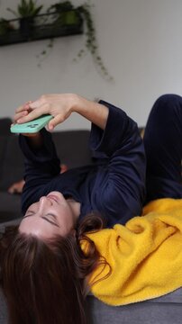 Vertical screen Waking up means reaching for her phone first as a young woman escapes into endless social media feeding instant dopamine before the day even begins