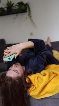 Vertical screen Mindless morning scrolling keeps a young woman glued to her phone as endless social media steals her focus and delays a fresh start to the day