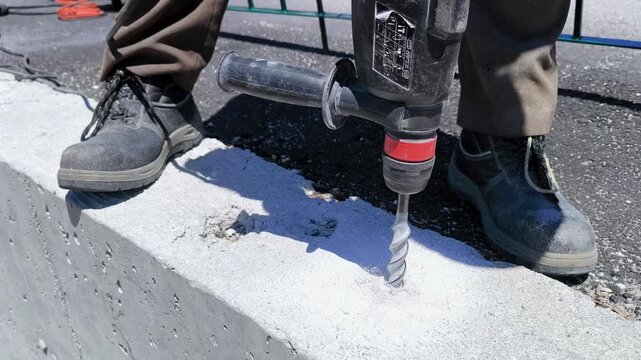 Trabalhador da constru&ccedil;&atilde;o civil a utilizar martelo perfurador com broca helicoidal para furar muro de bet&atilde;o para a instala&ccedil;&atilde;o de gradeamento
