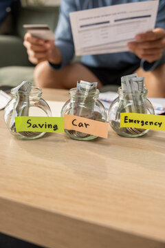 Saving car emergency jar money budget cash finance bill hand Jars with cash table for saving car emergency fund budget planning bill payment personal finance and household expense control Vertical