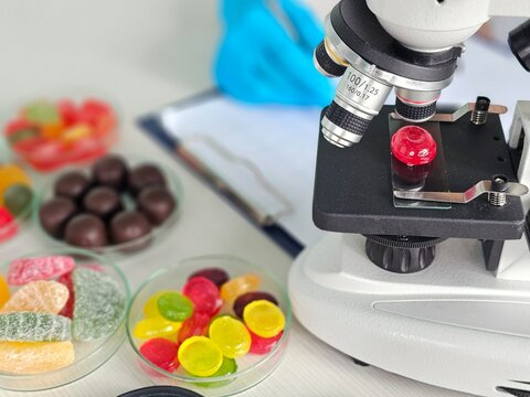 Microscope placed on table with colorful candies ready for examination in a lab