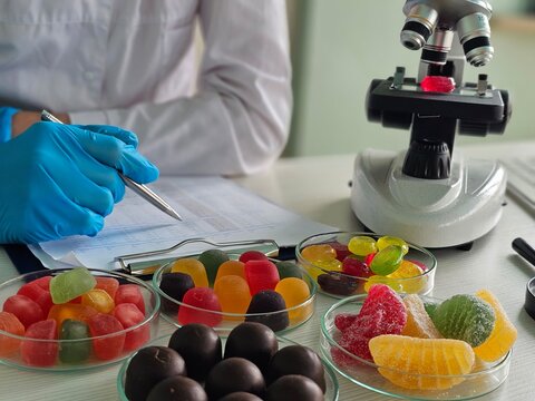 Scientist analyzes colorful candies under a microscope in a lab
