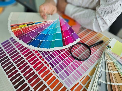 Choosing colors in a design studio while holding color swatches and examining options