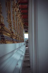 Fotobehang Gang Detailed perspective shot of ornate golden relief carvings on a white wall in a narrow temple passage  © Kooper