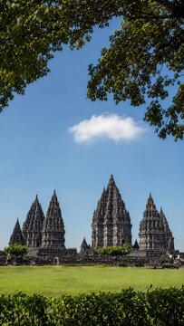 Ancient Prambanan Hindu Temple Spires Framed by Tree Branches Against Blue Sky, Central Java, Indonesia