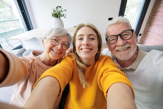Happy multigenerational family smiling for a selfie, bonding deeply and showing connection during a moment of love and happiness together in their bright home