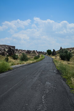 Empty rural road leading through fairy chimney rock formations in Devrent Valley, Cappadocia, Turkey
