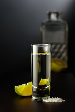 Mexican Tequila shot with lime and salt on black table.
