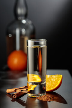 Mexican gold tequila with an orange slice and cinnamon on a black table.