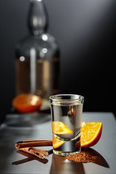 Mexican gold tequila with an orange slice and cinnamon on a black table.